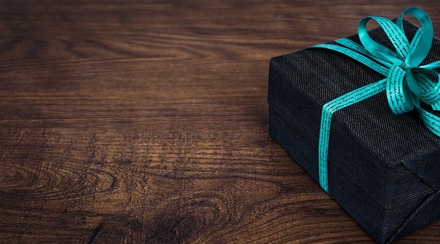 Čierna krabička s modrou stuhou – darček, na drevenom stole.jpg